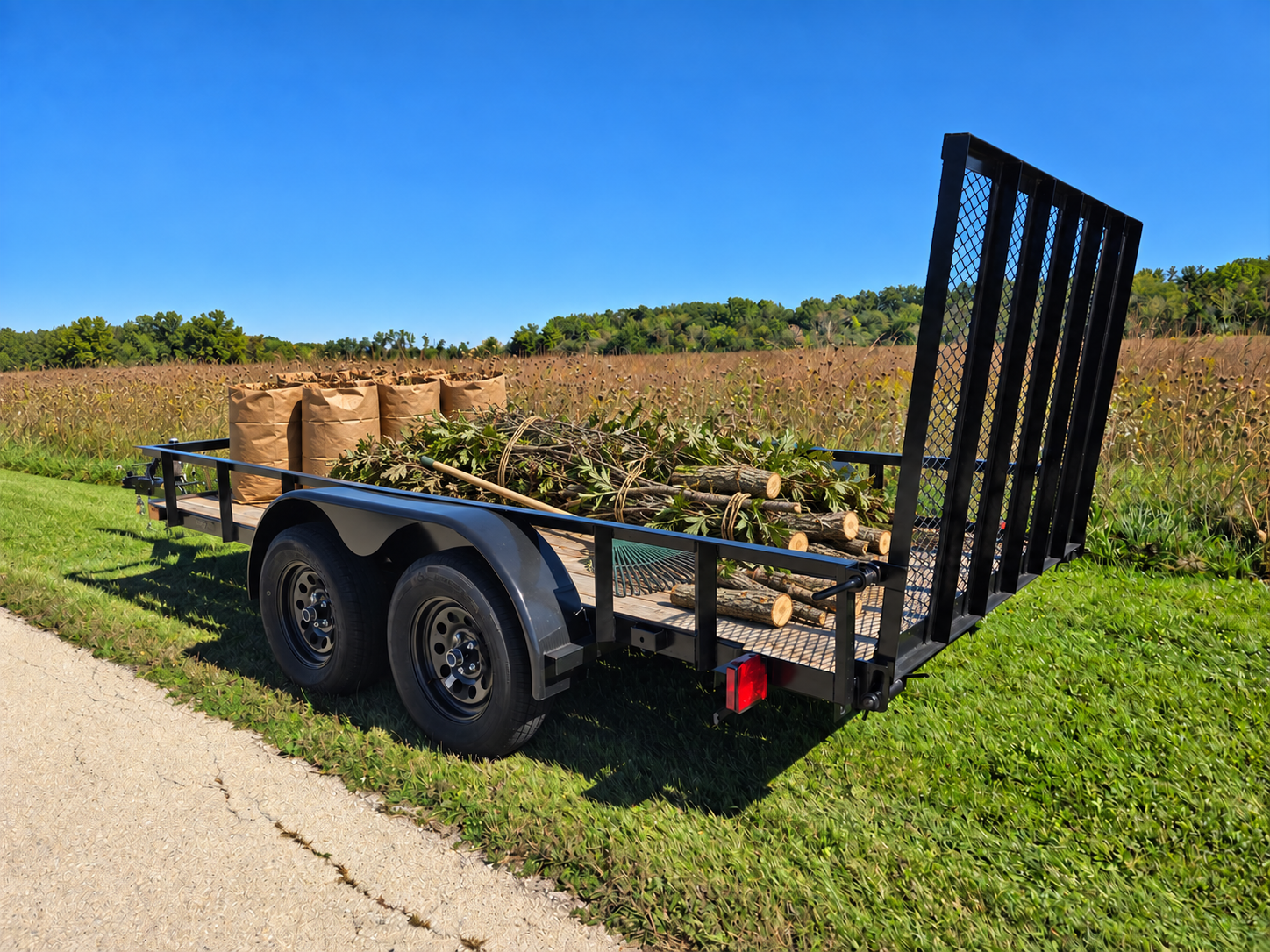 Trailer loaded with bagged leaves, bundled branches, cut logs and a rake
