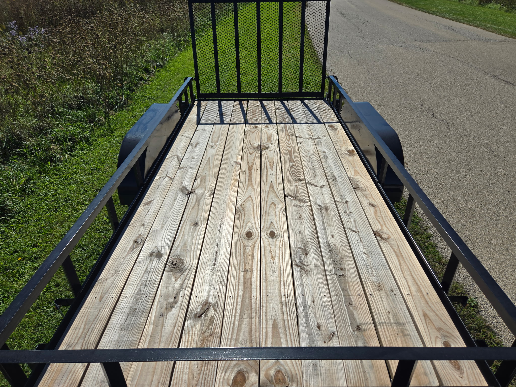 Top-down view of the wood plank deck and side rails with the mesh ramp gate raised