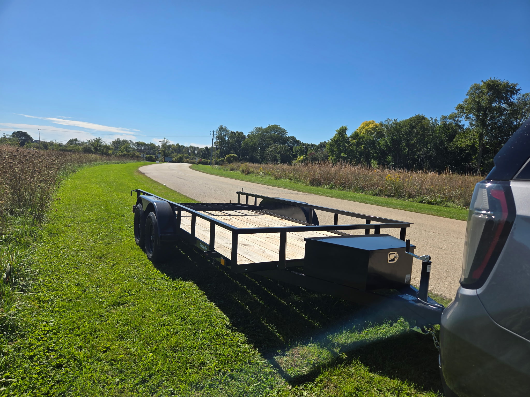 Trailer hitched behind an SUV along a curving road beside a prairie