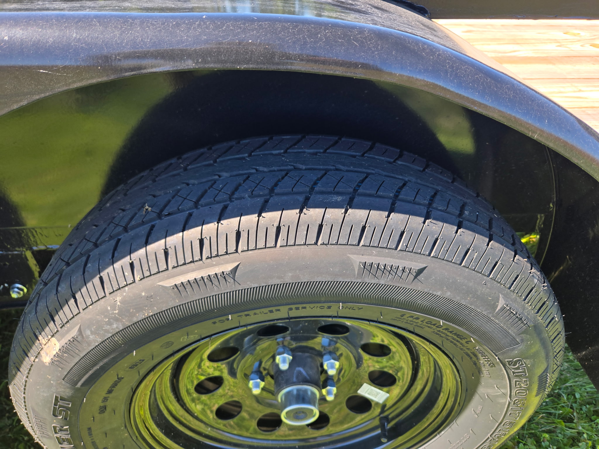 Close-up of a trailer tire and black steel wheel under the fender